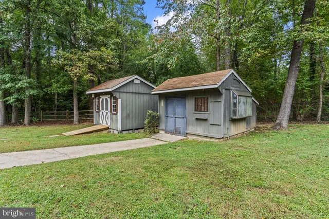 a view of a house with a yard and large trees