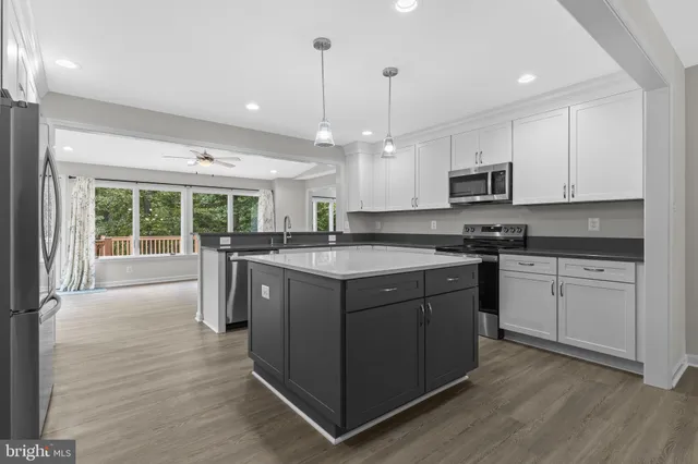 a kitchen with stainless steel appliances granite countertop a refrigerator a sink dishwasher a oven with white cabinets and wooden floor