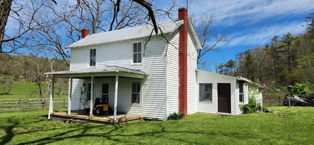 a view of a white house with a yard and large tree