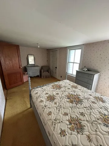 a bed sitting in a spacious bedroom next to a window and dresser