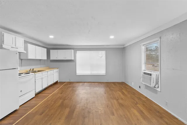 a large white kitchen with white cabinets and wooden floor