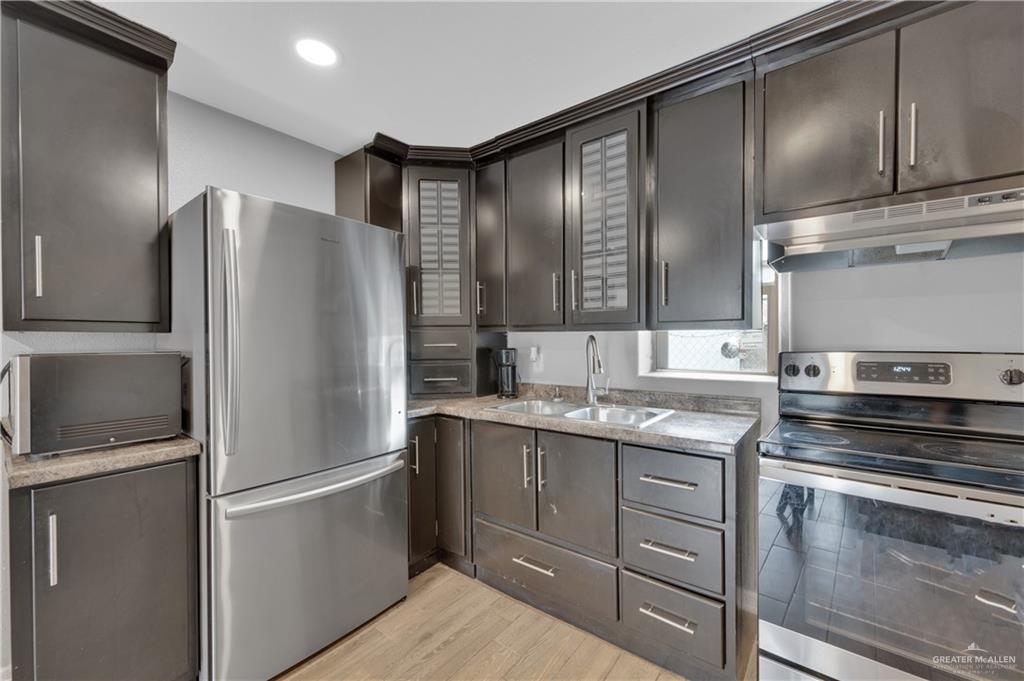 405 East Guerra Street Rio Grande City, TX 78582 - Photo 12 of 33 Kitchen featuring stainless steel appliances, a sink, under cabinet range hood, light wood-style floors, and recessed lighting