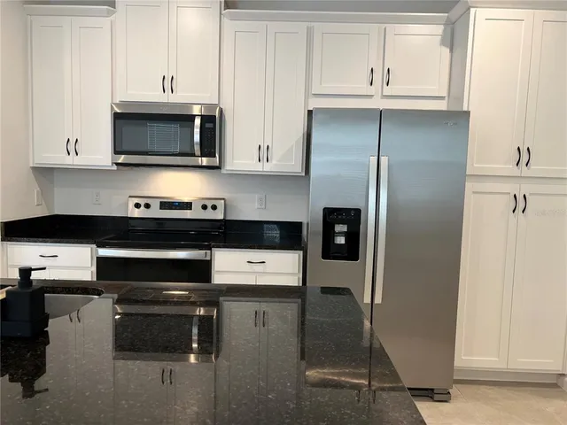 a kitchen with stainless steel appliances a refrigerator a stove and white cabinets