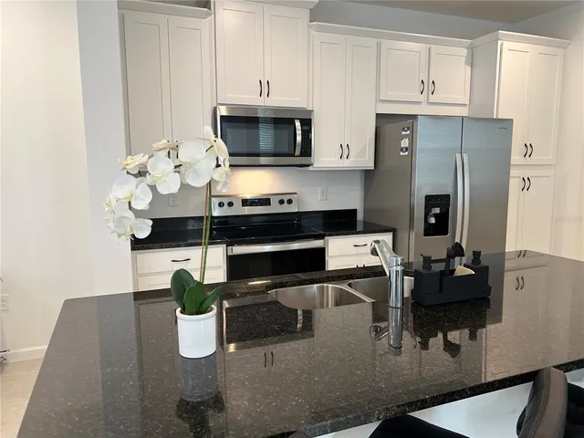 a kitchen with stainless steel appliances kitchen island granite countertop a refrigerator a stove a microwave and cabinets