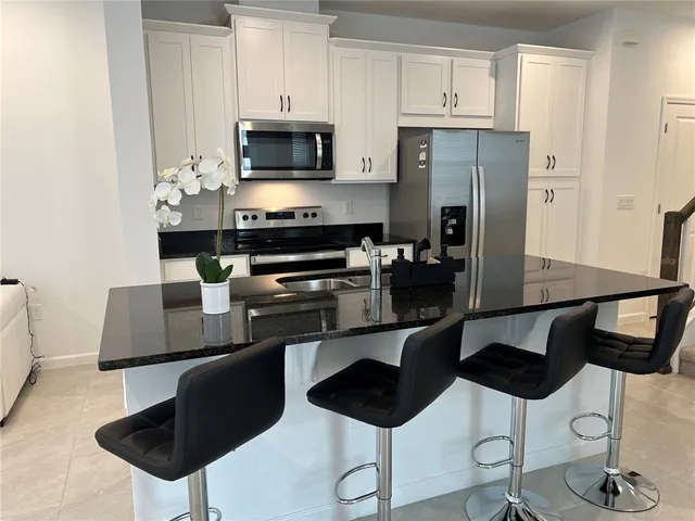 a kitchen with stainless steel appliances a stove a sink a microwave a refrigerator and white cabinets