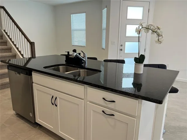 a kitchen with stainless steel appliances granite countertop a sink a counter space and a window