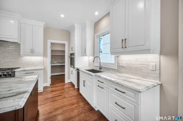 a kitchen with kitchen island granite countertop a stove a sink a center island and wooden floor