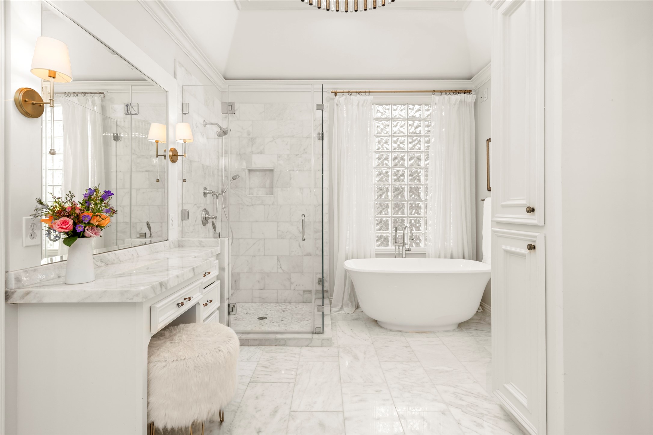 4220 Riley Street West University Place, TX 77005 - Photo 24 of 35 This view of the newly remodeled marble primary bathroom highlights the freestanding tub, seamless, frameless shower, timeless tile and the extra vanity with knee space offering a designated space for make-up application and hair magic!