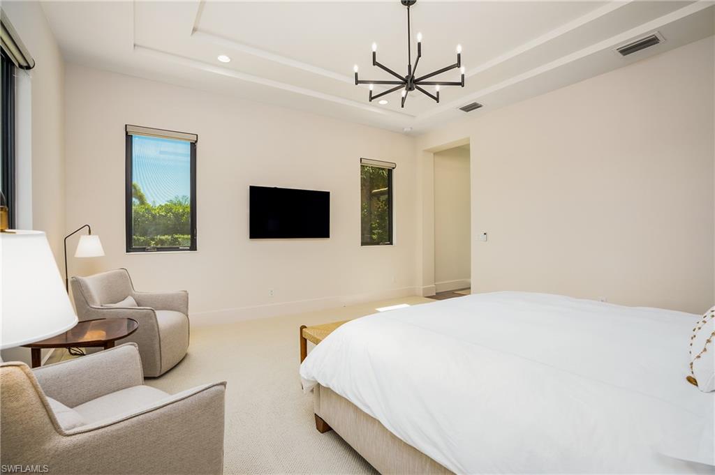 16708 Lucarno Way Naples, FL 34110 - Photo 34 of 46 a spacious bedroom with a bed and a flat screen tv