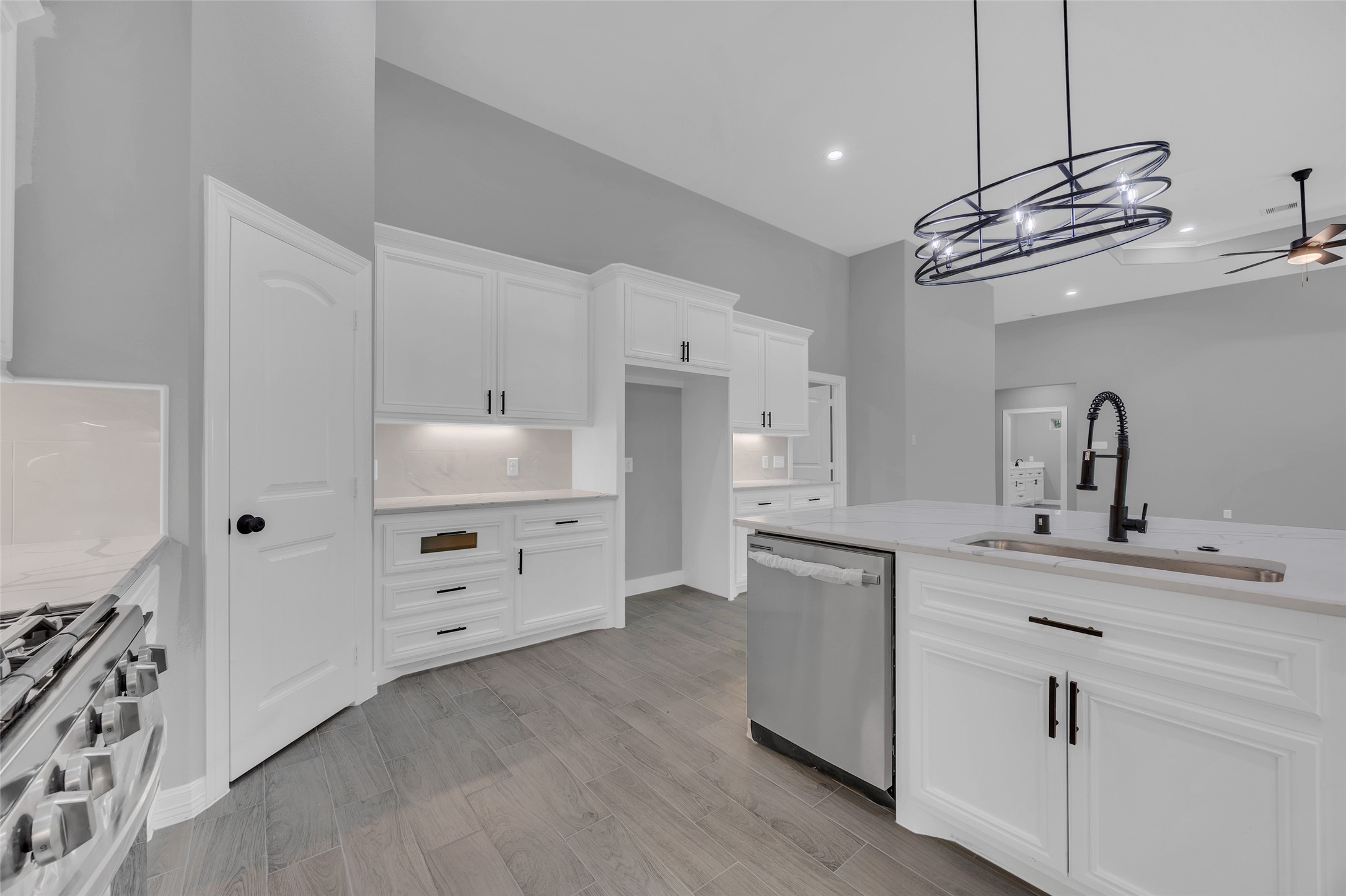 162 Bighorn Road Huntsville, TX 77340 - Photo 18 of 48 Modern kitchen featuring sleek white cabinetry, stainless steel appliances, and a stylish island with a contemporary pendant light. The open layout and neutral tones create a spacious and inviting atmosphere.