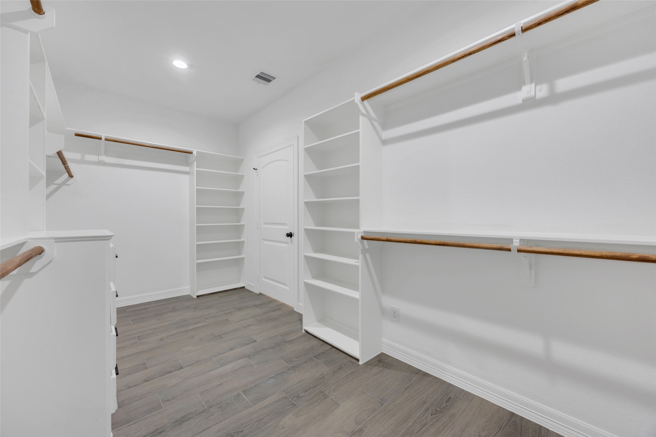 162 Bighorn Road Huntsville, TX 77340 - Photo 31 of 48 Spacious walk-in closet featuring ample shelving, hanging space, and wood-look flooring, perfect for organized storage in a modern, well-lit setting.