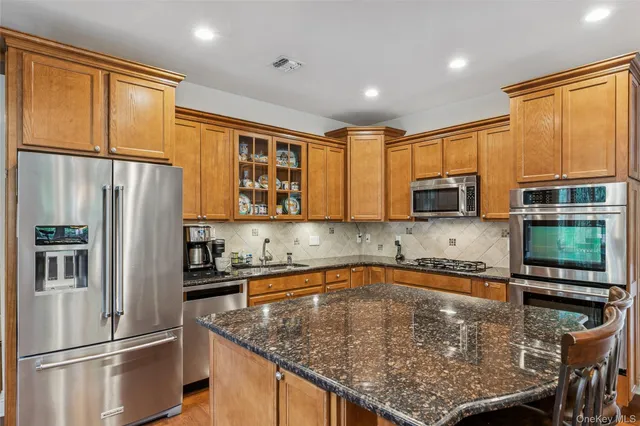a kitchen with stainless steel appliances granite countertop a refrigerator a stove top oven a sink and dishwasher
