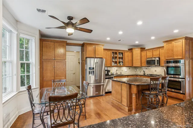 a kitchen with stainless steel appliances kitchen island granite countertop a dining table and chairs