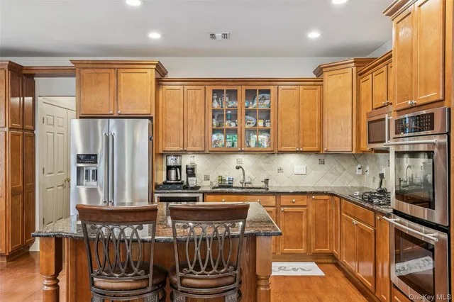 a kitchen with stainless steel appliances granite countertop a refrigerator a sink a stove and cabinets