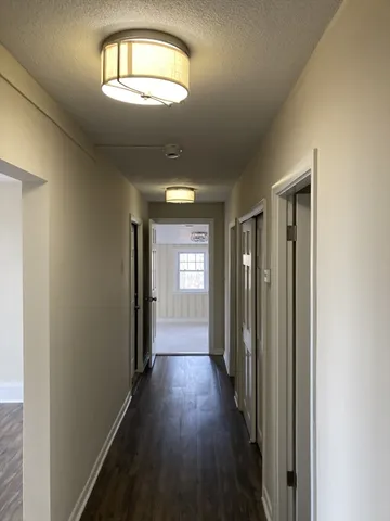 a view of a hallway with wooden floor and a chandelier