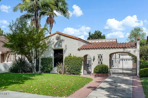 a view of a white house with a big yard and potted plants