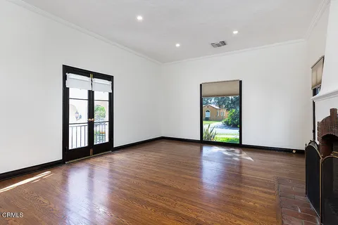 a view of an empty room with window and wooden floor