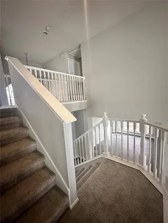 a view of staircase with railing and white walls