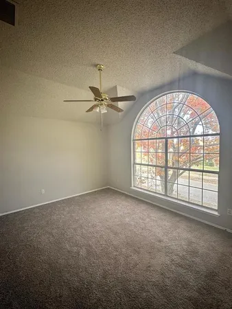 an empty room with windows and chandelier fan