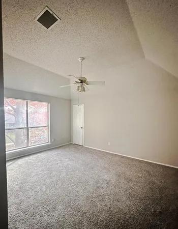 an empty room with windows and ceiling fan