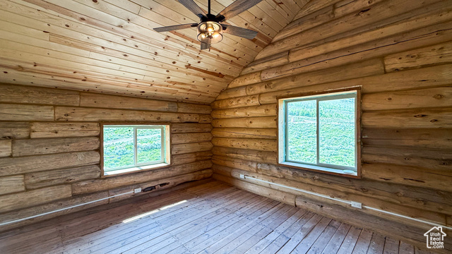 5236 North Holly Way Helper, UT 84526 - Photo 13 of 34 Empty room featuring ceiling fan, hardwood / wood-style floors, healthy amount of natural light, lofted ceiling, and rustic walls