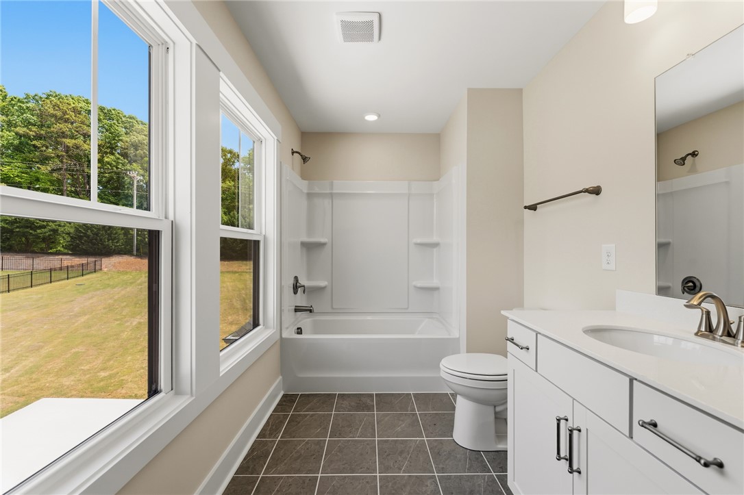 203 Timothy Court Anderson, SC 29621 - Photo 19 of 40 A well-lit bathroom, featuring a vanity with a sleek countertop and a combination shower-tub.