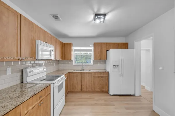 a kitchen with stainless steel appliances granite countertop a sink cabinets and wooden floor