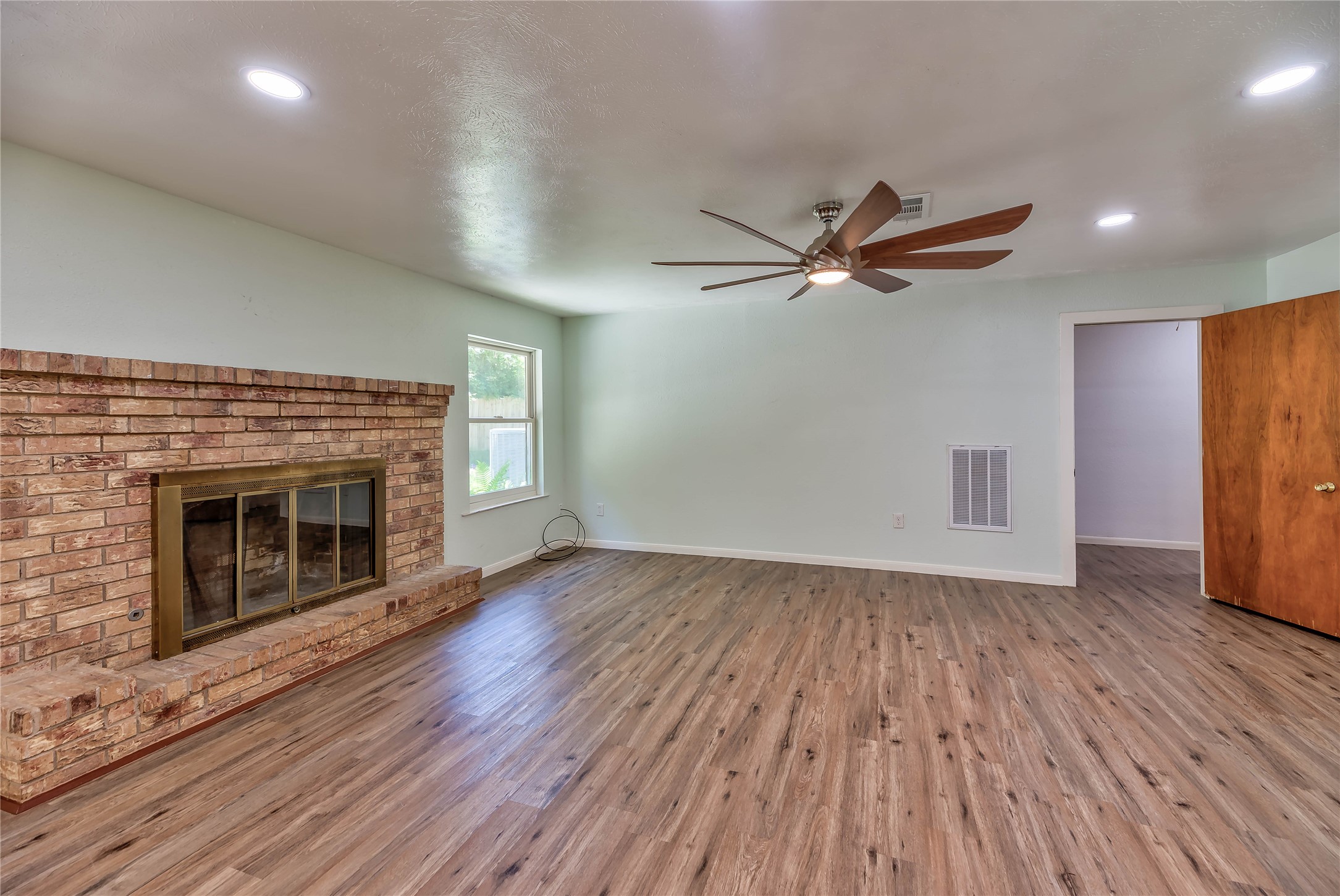 3003 Paul Knox Street Huntsville, TX 77320 - Photo 11 of 46 an empty room with wooden floor a fireplace and windows