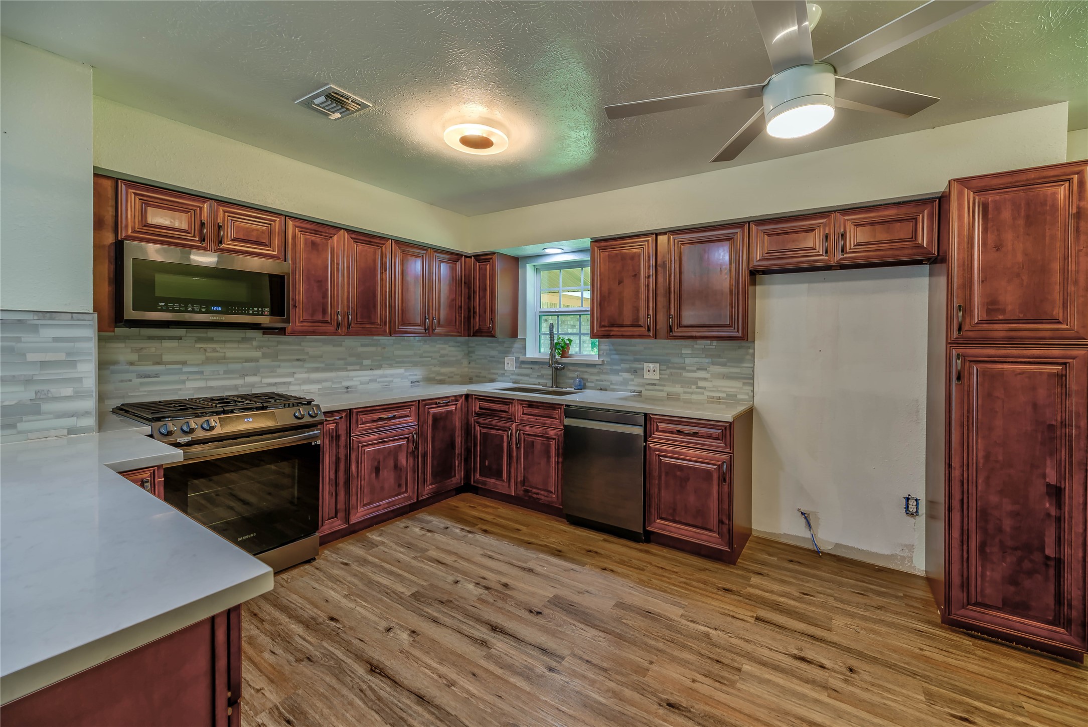 3003 Paul Knox Street Huntsville, TX 77320 - Photo 2 of 46 a kitchen with stainless steel appliances granite countertop wooden cabinets a stove top oven a sink and dishwasher a refrigerator with wooden floor