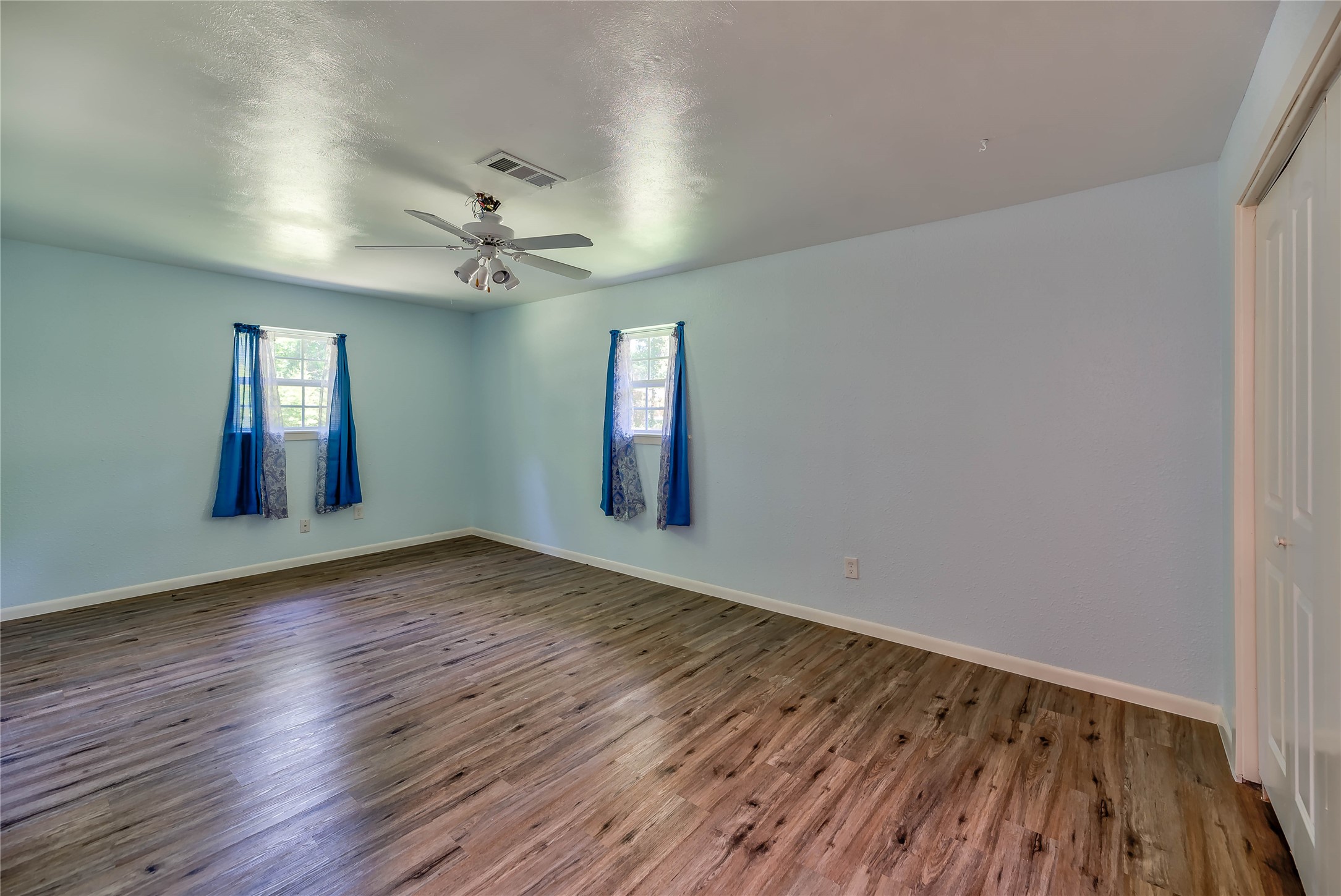 3003 Paul Knox Street Huntsville, TX 77320 - Photo 23 of 46 an empty room with wooden floor chandelier fan and windows