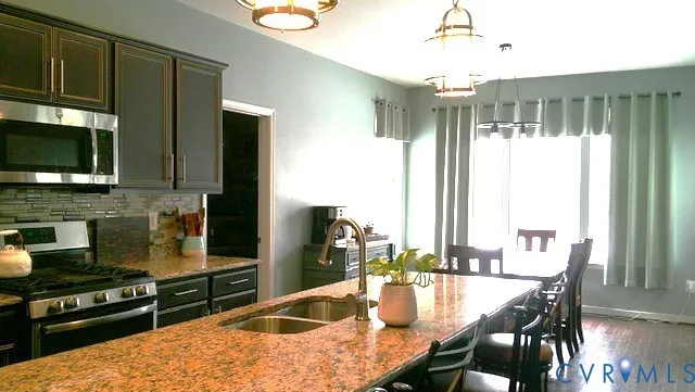 a kitchen with stainless steel appliances granite countertop a stove top oven a sink a dining table and chairs