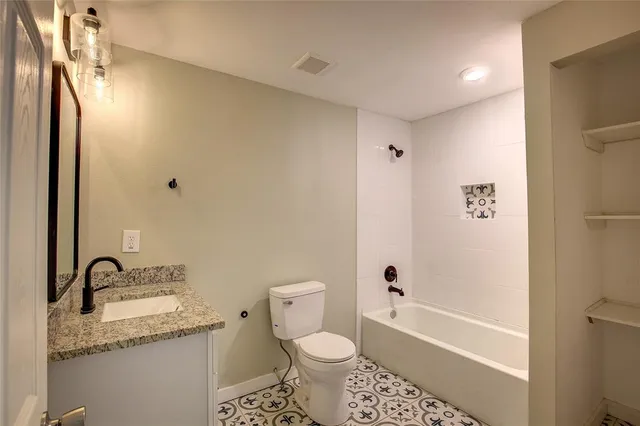 a bathroom with a granite countertop sink toilet and shower
