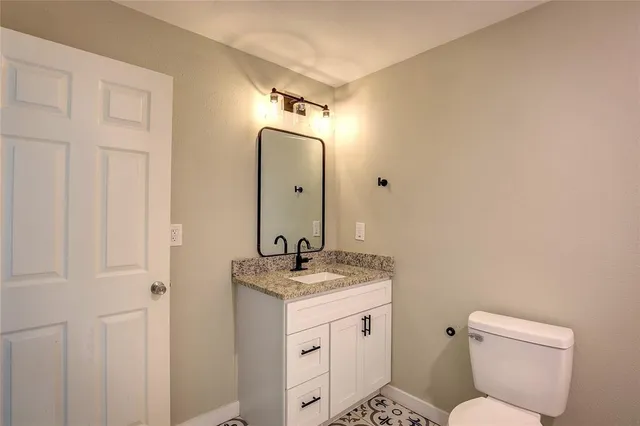 a bathroom with a granite countertop toilet sink and mirror