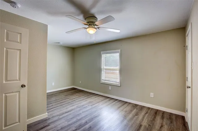 a view of an empty room with a window and wooden floor