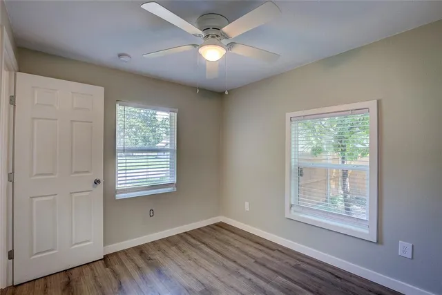 a view of an empty room with a window and wooden floor