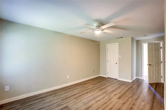 a view of a room with wooden floor and a ceiling fan