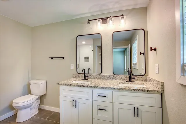 a bathroom with a granite countertop sink a toilet and a mirror
