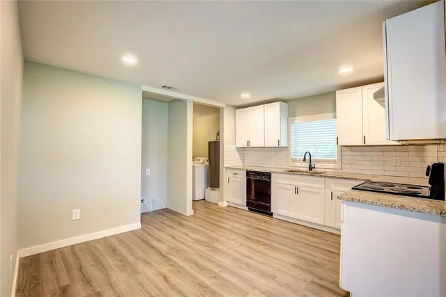 a kitchen with granite countertop a stove top oven sink and cabinets