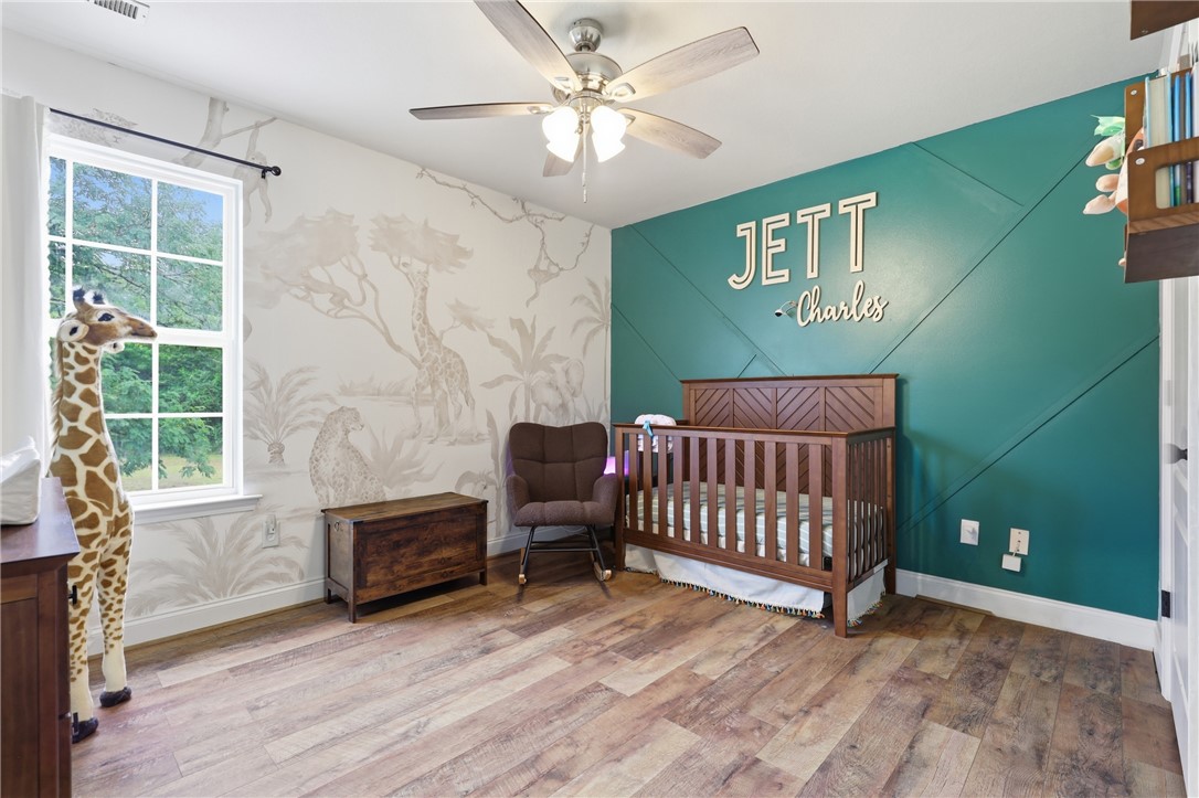 105 Lacy Lane Anderson, SC 29621 - Photo 12 of 16 A charming nursery features wood-look flooring and a unique accent wall, creating a serene and inviting atmosphere.