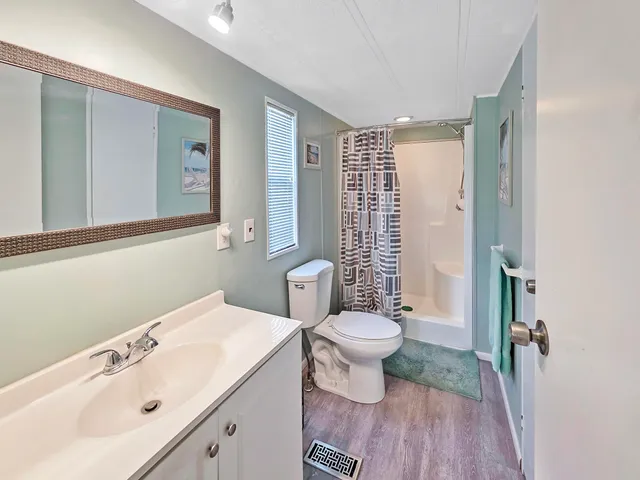 a bathroom with a sink a toilet a mirror and shower