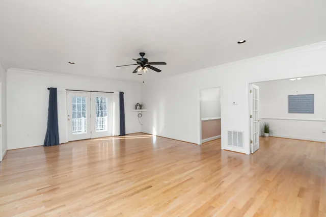 a view of an empty room with a window and wooden floor