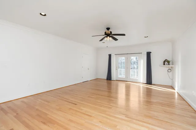 a view of an empty room with a window and wooden floor