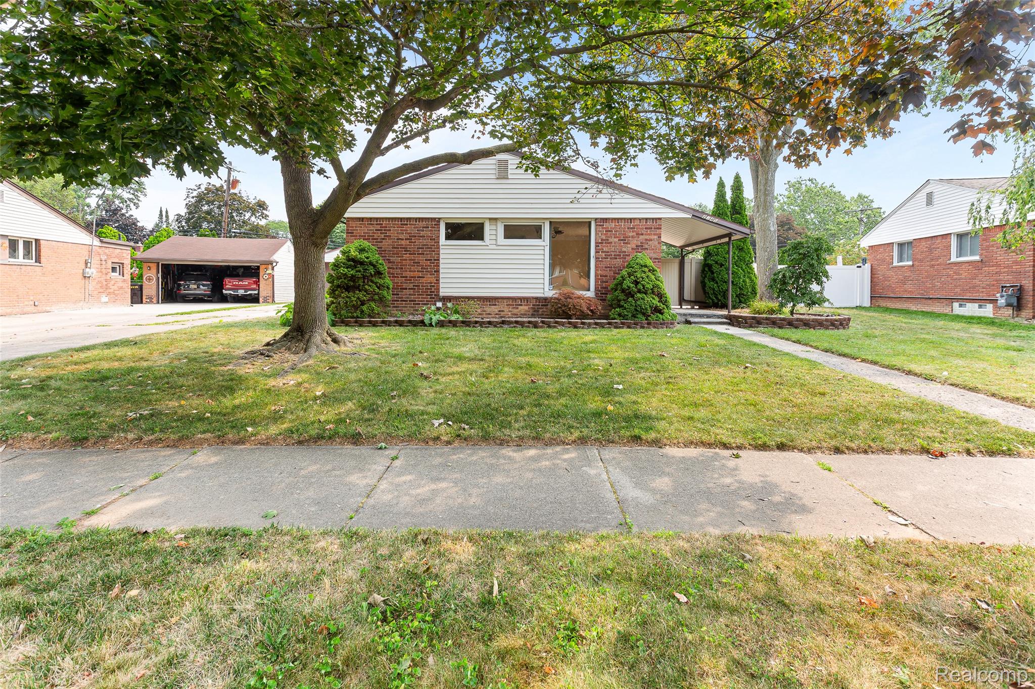 2345 Middlefield Road Trenton, MI 48183 - Photo 4 of 42 Brick and siding exterior featuring a front yard with mature trees, a concrete walkway, and a covered entry