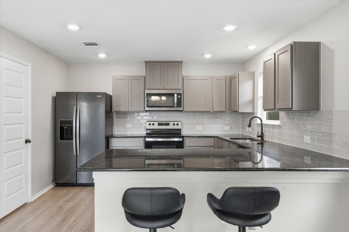104 Rooster Way Jarrell, TX 76537 - Photo 11 of 33 Gleaming stone countertops and modern cabinetry highlight this highly functional, open kitchen layout.