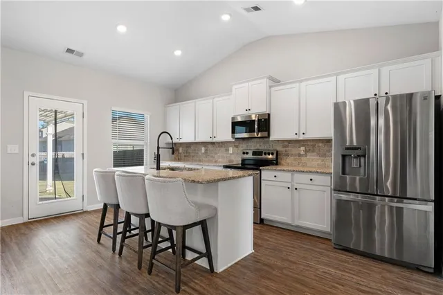 a kitchen with stainless steel appliances a dining table chairs microwave and refrigerator