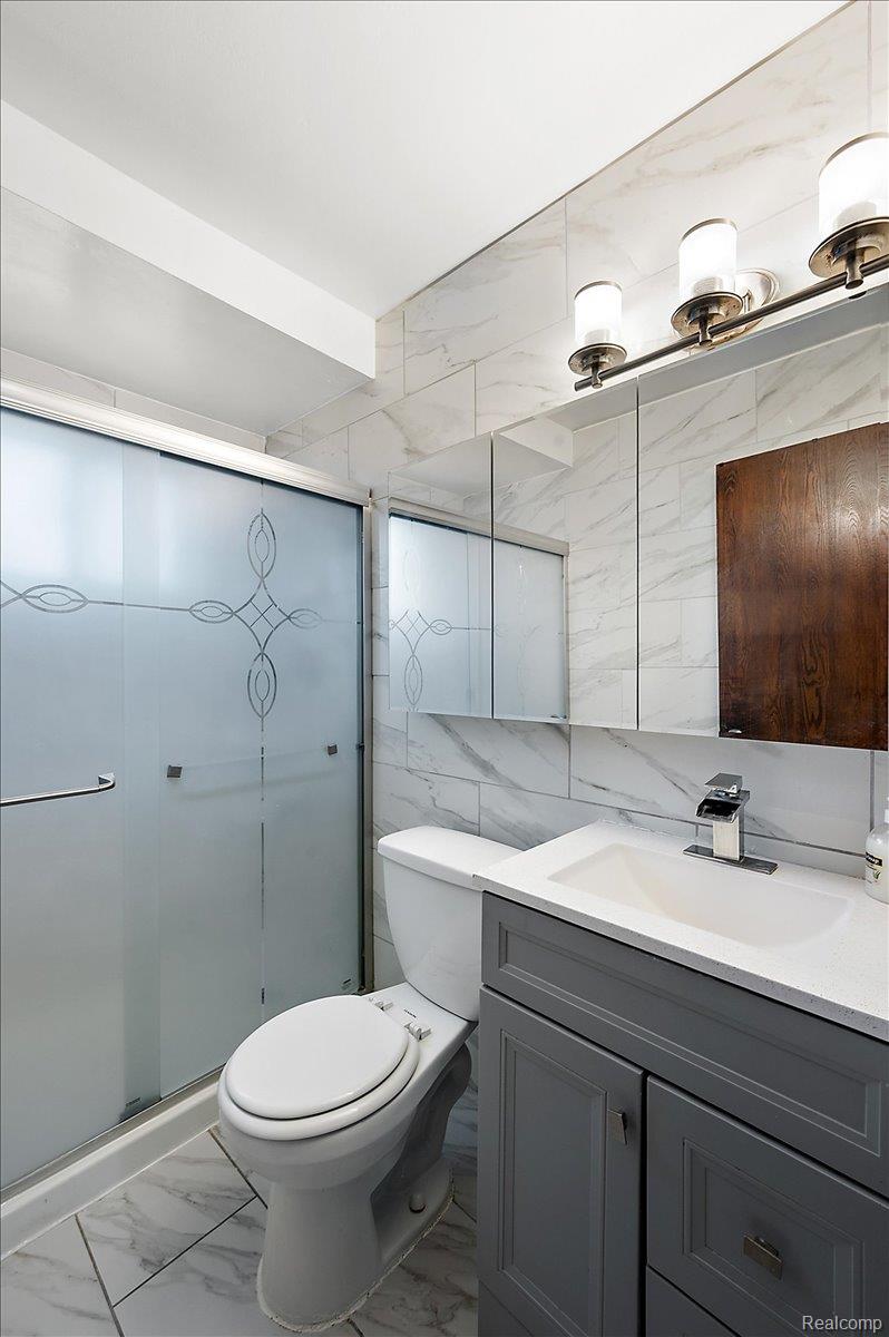 32416 Exeter Drive Warren, MI 48092 - Photo 26 of 33 Full bath featuring light marble finish flooring, vanity, tile walls, and a shower stall