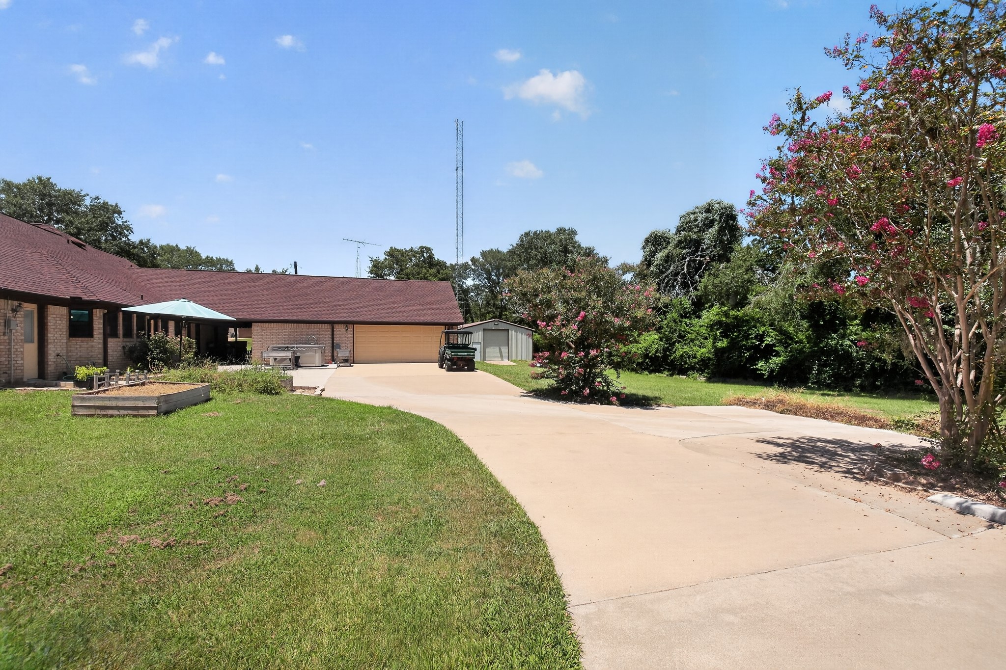 1950 Country Club Road Brenham, TX 77833 - Photo 6 of 39 A winding paved driveway leads to a brick home with an attached garage and a detached storage shed.