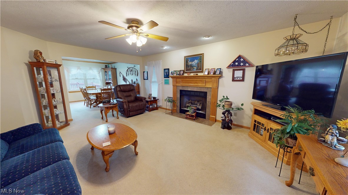 12431 Carter Road Painesville, OH 44077 - Photo 2 of 33 Living room with a textured ceiling, a tile fireplace, light colored carpet, and ceiling fan