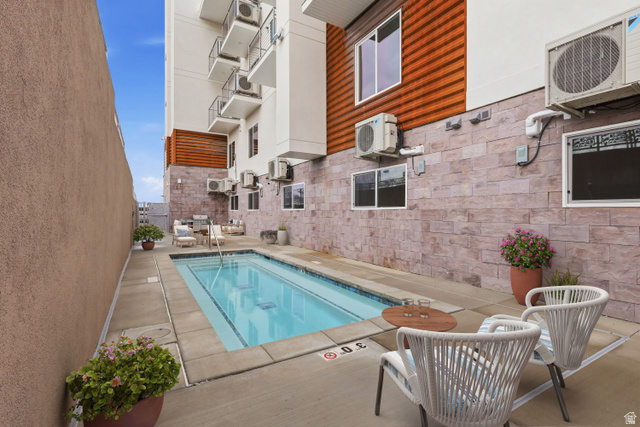 2085 North Main Street, Unit 216 Sunset, UT 84015 - Photo 8 of 12 Outdoor swimming pool surrounded by concrete decking and textured wall finishes, featuring a multi-story building exterior with balconies