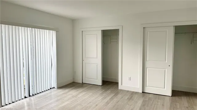 an empty room with wooden floor & windows